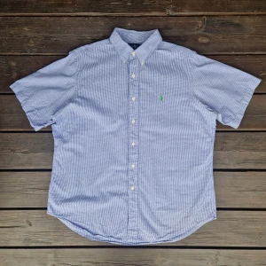 Ralph lauren skjorta L - 📊 Färg: Vit & Ljusblå  📏 Storlek: Large (L)  📐 Mått: Längd - 79cm Axelbredd - 50cm  ♻️ En långärmad Vit och ljusblå Ralph lauren skjorta i storlek L. Det står att den är I XL men den är mer som L. I väldigt bra skick, inga fläckar, hål eller defekter! Perfekt nu när det börjar bli varmare och sommaren kommer!☺️  👕 Material: 100% Bomull  #mensfashion #mensstyle #ralphlauren #classicstyle #buttondown #shirt #fashion #Vintage #Ralphlaurenskjorta