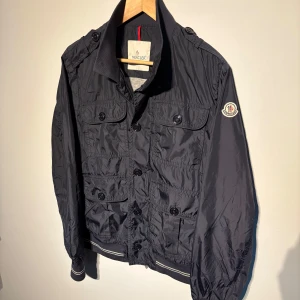 Moncler Jacka - En riktigt snygg field jacket från moncler i väldigt fint skick! Modell: ”Delonix”. Storlek 3 motsvarar S ungefär. Hör av er vid frågor!