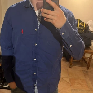 Ralph Lauren Skjorta - Säljer denna snygga mörkblåa Ralph Lauren skjorta med snyggt mönster vid knappar och krage. Skjortan är perfekt nu till sommaren. Storleken är M men den passar även S. Skriv vid funderingar.