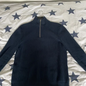Zara half zip - Mörkblå stickad tröja med hög krage och halv dragkedja framtill. Tröjan har lång ärm och ribbad struktur, perfekt för kyligare dagar. Enkel och stilren design som passar till mycket.