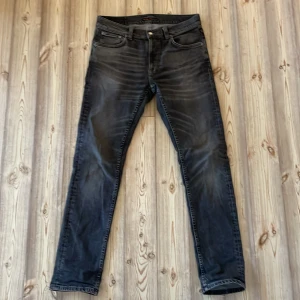 Svarta/gråa Nudie Jeans - Säljer ett par svarta jeans från Nudie Jeans nästan helt nya! Jeansen har en slimmad passform och är tillverkade i mjukt denimtyg. Perfekta för dig som gillar stilrena och tidlösa jeans. Pris kan diskuteras!