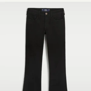Svarta bootcut jeans från Hollister - Svarta jeans från Hollister med bootcut-passform. Klassisk femficksdesign och knappgylf. Snygga och stilrena byxor som passar till många olika looks. Tydlig Hollister-logga på bakfickan och bakre linningen.