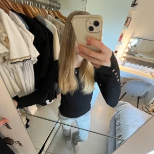 Svart långärmad tröja från Zara med guldknappar - Säljer en svart långärmad tröja från Zara med rund halsringning med guldknappar vid ärmsluten. Tröjan är i mjukt material och har en klassisk, enkel design som passar till mycket. Tröjan är i storlek S och är endast använd fåtal gpnher därav i mycketbra skick. 