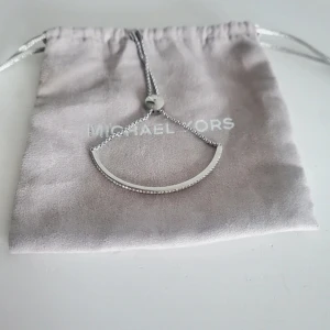 armband från Michael Kors - stilrent armband från Michael Kors i silverfärg med glittriga stenar på framsidan. Armbandet har en justerbar kedja med lås