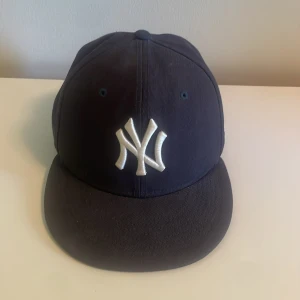 Mörkblå New Era New York Yankees keps - Säljer en mörkblå New Era 59FIFTY keps med New York Yankees-logga broderad framtill i vitt. Klassisk rak skärm och broderad New Era-logga på sidan. Storlek 7 1/8 (56,8 cm). Hör av dig vid funderingar!