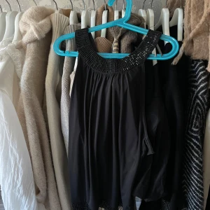 Fest topp - Säljer en svart fest topp med dekorativ kant runt halsringningen. Toppen har ett ganska mjukt, lätt tyg. 