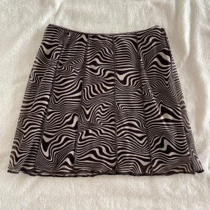 Brun och beige mönstrad kjol från h&m - Kortkjol från Divided med brunt och beige zebramönster. Kjolen har en lätt utsvängd form och är tillverkad i ett mjukt syntetmaterial med fodrad insida. Perfekt för dig som gillar att sticka ut med coola mönster. Längd: 36cm, Midja: 31cm