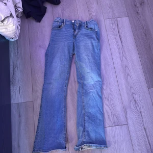 Blå bootcut jeans från Ginatricot - Säljer ett par ljusblå jeans från gina! Dom är använda ganska mycket men är fortfarande i bra skick. Dom är ganska långa och stor i storleken! Har lite små hål där nere i byxkanten men annars är dom bra! Köpta för 400kr💞