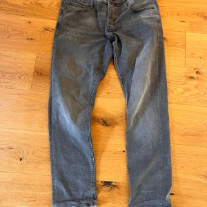 Grå slim fit jeans från Jack & Jones - Grå jeans från Jack & Jones i modellen Slim/Glenn. Byxorna har klassisk femficksdesign, dragkedjegylf och smal passform. Perfekta för dig som gillar en stilren och enkel look.