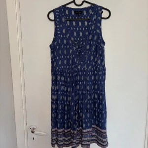 Blå mönstrad klänning - Somrig blå ärmlös klänning från New Look med fint mönster och snörning framtill. Perfekt för skolavslutningen! Klänningen passar storlek (36/38). Fråga gärna vid fler funderingar! 💙