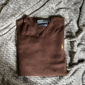  Tröja från Polo Ralph Lauren - Säljer en brun v-ringad tröja från Polo Ralph Lauren i 100% pima bomull. Klassisk design med broderad logga på bröstet. Perfekt för dig som gillar stilrena och tidlösa plagg. Bara att höra av sig för fler bilder eller funderingar.
