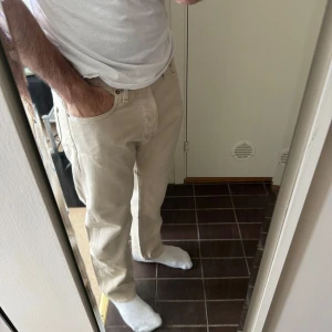 Beige raka jeans - Säljer ett par beige jeans med rak passform. Klassisk femficksmodell med dragkedja och knapp i midjan. Perfekta till vardags och lätta att matcha med olika stilar.