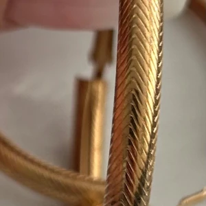 Guldfärgade creoler med fiskbensmönster - Säljer ett par stora, runda örhängen i guldfärg med snyggt fiskbensmönster. Creolerna har ett klassiskt lås och är perfekta för att lyfta din stil med en elegant touch.