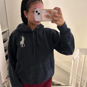 Mörkblå hoodie från Ralph Lauren - Säljer en mörkblå hoodie från Ralph Lauren med stor vit polospelare-logga på bröstet och siffran 3 på ärmen. Tröjan har huva med dragsko och en stor magficka framtill.