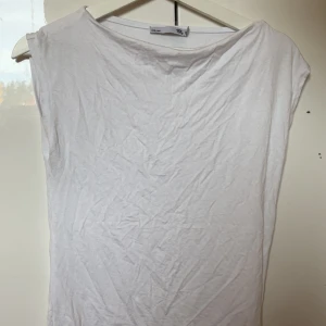 Vit ärmlös linnetopp - En enkel och stilren vit linnetopp med ärmlös design. Perfekt för varma dagar och lätt att matcha med olika outfits. Toppens material känns mjukt och luftigt.