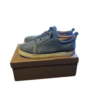 Blåa sneakers med nitar från Christian Louboutin - Säljer ett par blåa sneakers från Christian Louboutin med coola silverfärgade nitar på tån. Skorna har snörning och den klassiska röda sulan. Perfekta för dig som vill sticka ut med din stil. Skorna är väldigt sällsynta i just denna färgkombinationen! 100% äkta kvitto finns och skickas med! Skicka prisförslag och kom med bud om priset ej passar är villig o ge ner i pris!!