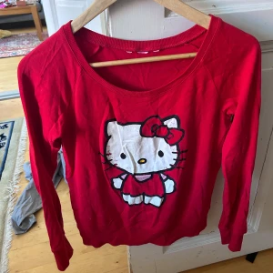 Röd Hello Kitty tröja st S - Säljer en röd långärmad tröja med stort Hello Kitty-tryck framtill. Tröjan har rund halsringning och är i mjukt bomullsmaterial. Perfekt för dig som gillar söta och färgglada plagg! Titta på trycket! 