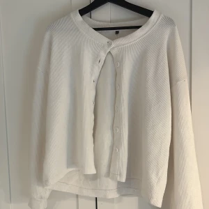 Vit ribbad kofta med knappar - Säljer en vit ribbad kofta med långa ärmar och rund hals. Koftan har knäppning framtill med flera knappar och är tillverkad i ett mjukt, bekvämt material. Perfekt för lager-på-lager och enkel att matcha med olika outfits. I acceptabelt skick!🥰