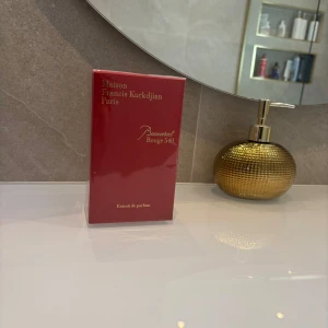 Baccarat Rouge 540 Extrait de Parfum - Lyxig parfym i röd och guld förpackning från Maison Francis Kurkdjian, Baccarat Rouge 540 Extrait de Parfum. Kartongen har elegant gulddetaljer och illustration av en byggnad på sidan. Perfekt för dig som vill ha en exklusiv doftupplevelse. Inget kvitto helt nytt 