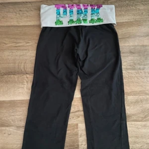Victoria’s Secret Rare - Snygga Victoria’s Secret PINK yoga-byxor. På baksidan av midjan står det “PINK” i glittriga paljetter i regnbågsfärger. Går ner till knäna, perfekta för träning, lounging eller vardag. Sköna, stretchiga och i fint skick! Rare/Limited edition   ⸻     Storlek: xs Skick: Mycket bra, inga synliga defekter  ⸻  victoria’s secret, pink, yoga pants, träningstights, capri leggings, glittriga byxor, regnbågsfärger, paljetter, svartvita, knälånga, mjuka, bekväma, sportmode, trendiga, damkläder
