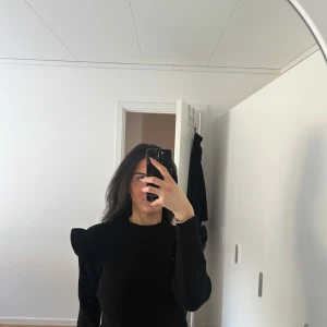 Svart ribbad tröja med puffärmar från OBJECT - Säljer en svart ribbad tröja från OBJECT med markerade puffärmar och rund halsringning. Tröjan har en tight passform och är långärmad, perfekt för att lyfta en enkel outfit.