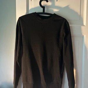Svart sweatshirt från Divided - En enkel svart sweatshirt från Divided med rund halsringning och långa ärmar. Perfekt baströja som passar till det mesta. Mjuk och bekväm med ribbade muddar vid ärmslut och nederkant.