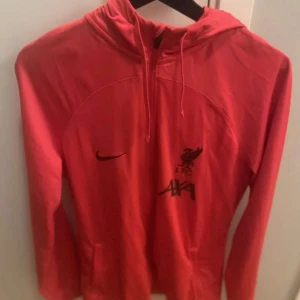 Röd Liverpool hoodie från Nike - Säljer en skön röd liverpool tröja. Tröjan passar perfekt till träning. Storleken är i M men passar även L. Skick 10/10 då jag in använder tröjan längre. Skriv vid funderingar!