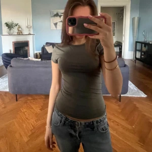 Olivgrön tight t-shirt - Säljer en enkel olivgrön t-shirt med rund halsringning. Använd få gånger. 