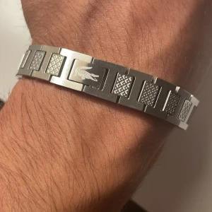 Silverfärgat armband från Lacoste - Jag säljer mitt armband från Lacoste, fick den av mitt Ex, vill ej behålla den längre på grund av minen. Vill bli av med den. Äkta Lacoste. Original pris 1099kr. Hör av er 😊
