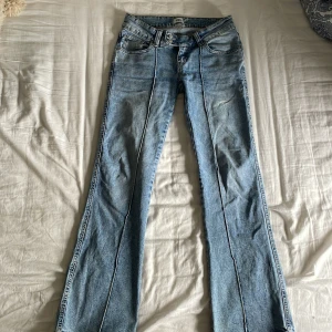 Bootcut jeans i ljusblå denim 157 S - Snygga bootcut jeans från 157 i ljusblå denim. Byxorna har en liten vit fläck, vet ej vad det är men är ej märkbar. De är ganska low waist för att komma från lager 157. Köpare står för frakt