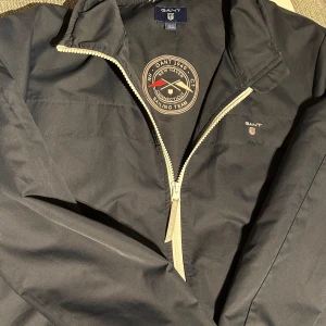 Gant vindjacka  - Sportig och stilren vindjacka från Gant – perfekt för blåsiga dagar och svalare väder. Lätt och smidig att bära med klassisk design, dragkedja, och diskret Gant-logo. Passar lika bra till vardags som till en aktiv livsstil. En mångsidig jacka som funkar året runt! Fräsch, ren och redo för användning!