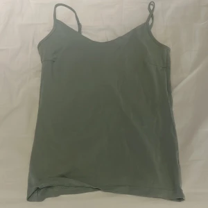 Ljusgrön linnetopp från Lager 157 med smala axelband - En stilren grå linnetopp från 157 i storlek M. Toppen har smala justerbara axelband och är tillverkad i mjuk bomull med lite stretch för skön passform. Perfekt att matcha med jeans eller shorts för en chill look.