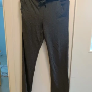 Svarta mjukisbyxor med snörning - Svarta mjukisbyxor med dragsko i midjan och fickor. Sköna och enkla, perfekta för chill eller träning. Raka ben och mjukt material som känns bekvämt hela dagen.