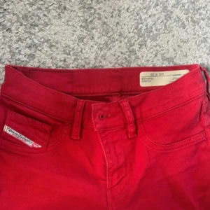 Röda Diesel Livier byxor - Säljer ett par röda Diesel Livier super slim-jeggings med låg midja. Byxorna är stretchiga med Diesel-logga på fickan. 
