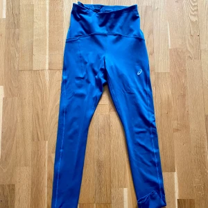 Blå/gröna tights från Asics - Snygga blå/gröna träningstights från Asics med hög midja och snörning.  Perfekta för löpning eller gymmet! Litet hål på ena sidan, se sista bilden.