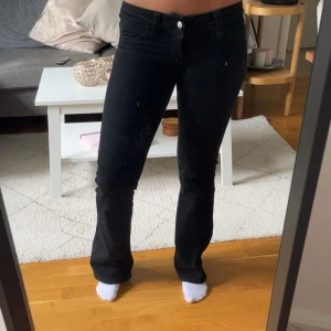 Svarta bootcut jeans - Säljer ett par svarta jeans med bootcut-modell och klassisk femficksdesign. Jeansen är lågmidjadd och är tillverkade i ett stretchigt bomullsmaterial som sitter snyggt över höfterna och låren. Perfekta för dig som gillar en tidlös och clean look.