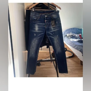 Dsquared2 blå  jeans - Snygga blå jeans från Dsquared2 med slitna detaljer och skinny passform. Jeansen har klassisk femficksdesign, tydliga slitningar framtill och Dsquared2-logga bak på linningen. Perfekta för dig som gillar en modern och trendig look.
