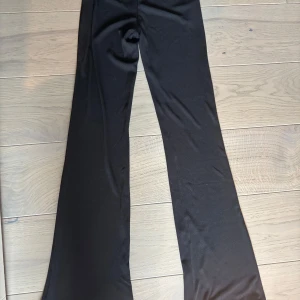 Svarta bootcut byxor i stretch - Svarta byxor med bootcut-modell och stretchigt material. Snygg passform som sitter tajt upptill och släpper ut vid benen. Perfekta till sneakers eller boots för en clean look.