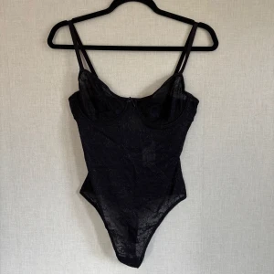 Svart spetsbody - Supersnygg svart, spetsbody från NA-KD i storleken 75C. Säljer pga den var fel storlek för mig, men tycker själv den är superfin! Helt oanvänd såklart och alla prislappar och skydd sitter kvar. (Den har inga knappar och man måste dra på den nedifrån, har själv ganska breda höfter så det var problemet för mig, så bara en liten heads-up.) ☺️