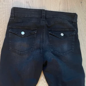 Svarta bootcut jeans - Svarta jeansbyxor från Gina Tricot med bootcut-passform. Byxorna har klassiska fem fickor, silverfärgade knappar och låg midja. 