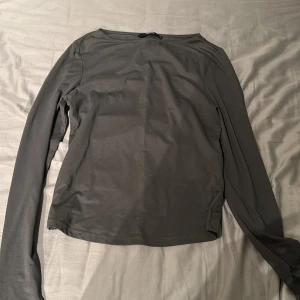 Mörkgrå långärmad topp från BikBok - Säljer en enkel och stilren mörkgrå långärmad topp från BikBok. Modellen är rak med rund halsringning och tillverkad i ett mjukt, stretchigt material. Perfekt att matcha med jeans eller kjol.