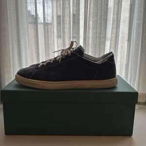 Navy blue sneakers i mocka från CQP - Säljer ett par Navy blue sneakers från CQP i mocka med vita snören och vit sula. Skorna har en klassisk låg profil och diskret logga på innersulan. Perfekta för dig som gillar stilrena och sköna sneakers.