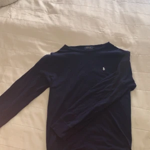 Långärmad Ralph Lauren  - Säljer en klassisk mörkblå långärmad tröja från Polo Ralph Lauren med den ikoniska broderade loggan på bröstet. Tröjan är i mjuk bomull och har en normal passform. Perfekt till många olika tillfällen.Mörkblå långärmad tröja från Polo Ralph Lauren
