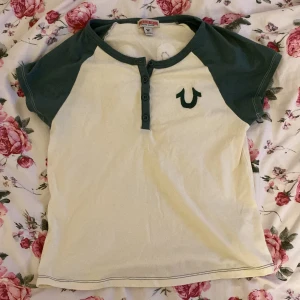 vit och grön t-shirt från True Religion - jätte fin true religion t-shirt som är köpt från urban outfitter. tröjan är i jätte bra skick eftersom jag bara har haft på mig den en gång. storlek S men den passar XS med. den är lite kort men inte riktig en magtröja! :) skriv om du vill diskutera priset