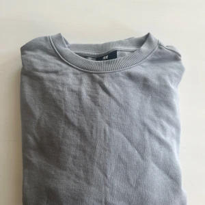 Grå sweatshirt från H&M - Säljer en enkel och stilren grå sweatshirt från H&M i relaxed fit. Tröjan har rund halsringning och är perfekt för en avslappnad look. Passar till det mesta och är ett måste i garderoben. Skick är 10/10 då den aldrig används.