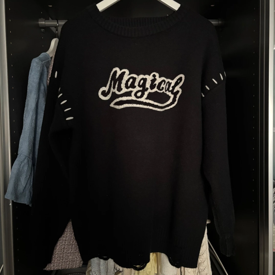 Svart stickad tröja med texten 'Magical'