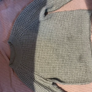 Ljusgrå stickad tröja från 157 - Mysig ljusgrå stickad tröja från 157 i storlek XS. Tröjan har ett grovt stickat mönster, rund halsringning och långa ärmar. Perfekt för kyligare dagar och enkel att matcha med olika outfits.