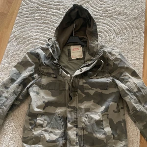 Jacka  - Säljer en snygg camouflagefärgad jacka från Jack & Jones. Jackan har huva, dragkedja och flera fickor framtill. Har inte använts många gånger så är i väldigt bra skick.                                     Det är bara att höra av er vid frågor 🙂
