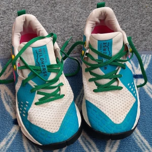 Nike Wildhorse trail sneakers med färgglada detaljer - Nike Wildhorse sneakers med vit mesh, blå och turkosa paneler, gröna skosnören och färgglada detaljer i rosa, gul och svart. Skorna har en robust sula med bra grepp, perfekt för trail och utomhusaktiviteter. Skor är mycket lätta och bekväma i mycket bra skick. Skor har inga skador. 