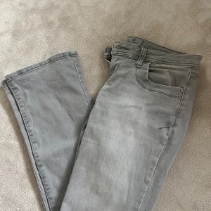 Grå jeans med låg midja - Säljer ett par grå jeans med låg midja. Byxorna har normal passform med snygga detaljer på bakfickorna och diskret tvättad finish.